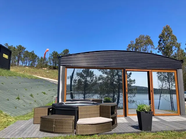Air Fervenza: Jacuzzi exterior sobre una terraza de madera, junto a una estructura con grandes ventanales y puertas de cristal que dan