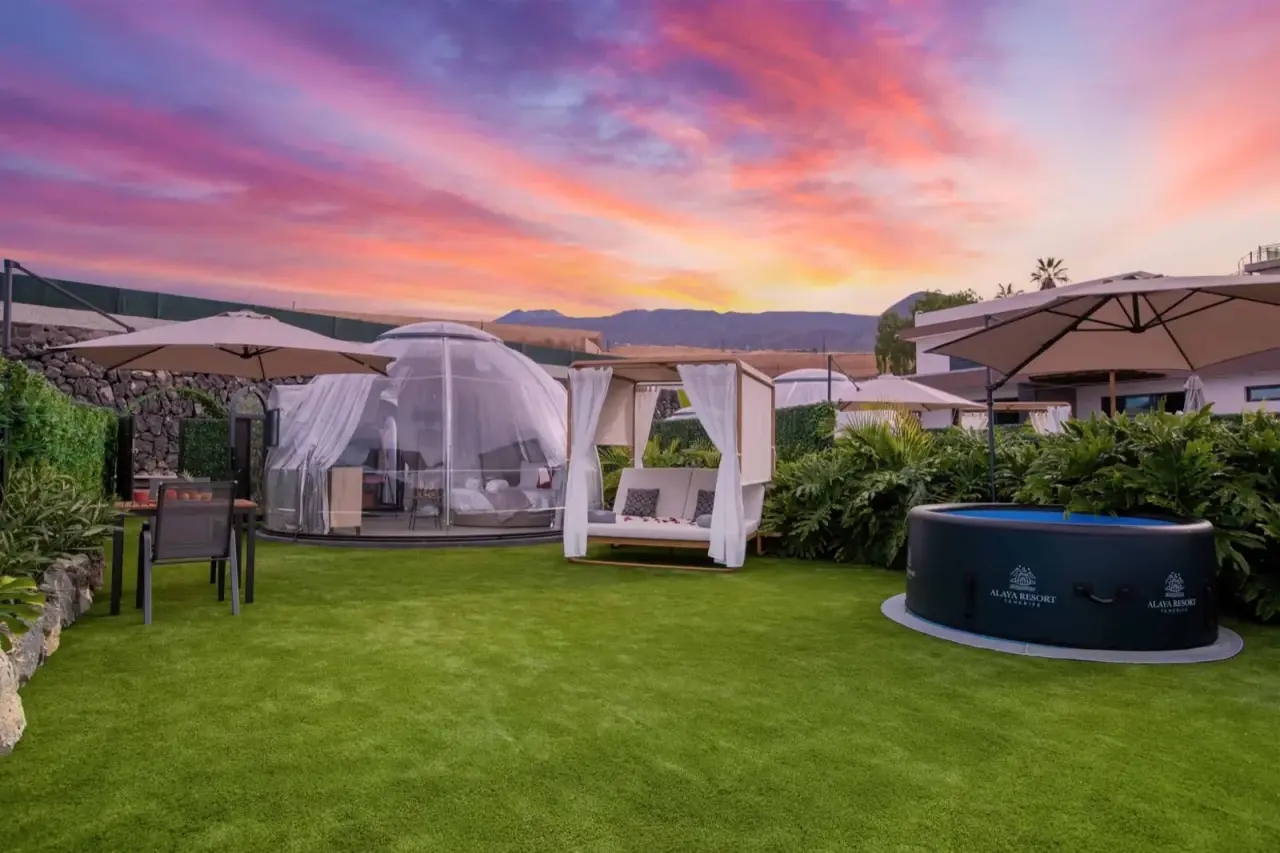 Vista de un jacuzzi privado inflable de color negro situado en un jardín de césped, junto a una cúpula transparente