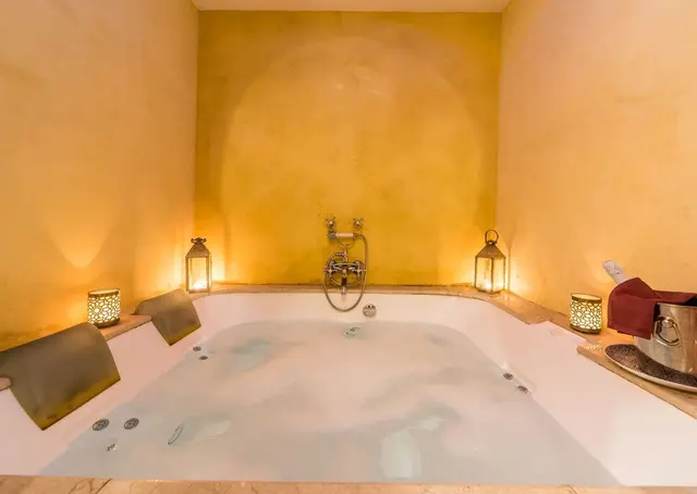 Hotel Alcoba del Rey: Jacuzzi rectangular empotrado en una habitación con paredes de color ocre. El agua está en movimiento con burbujas. En l