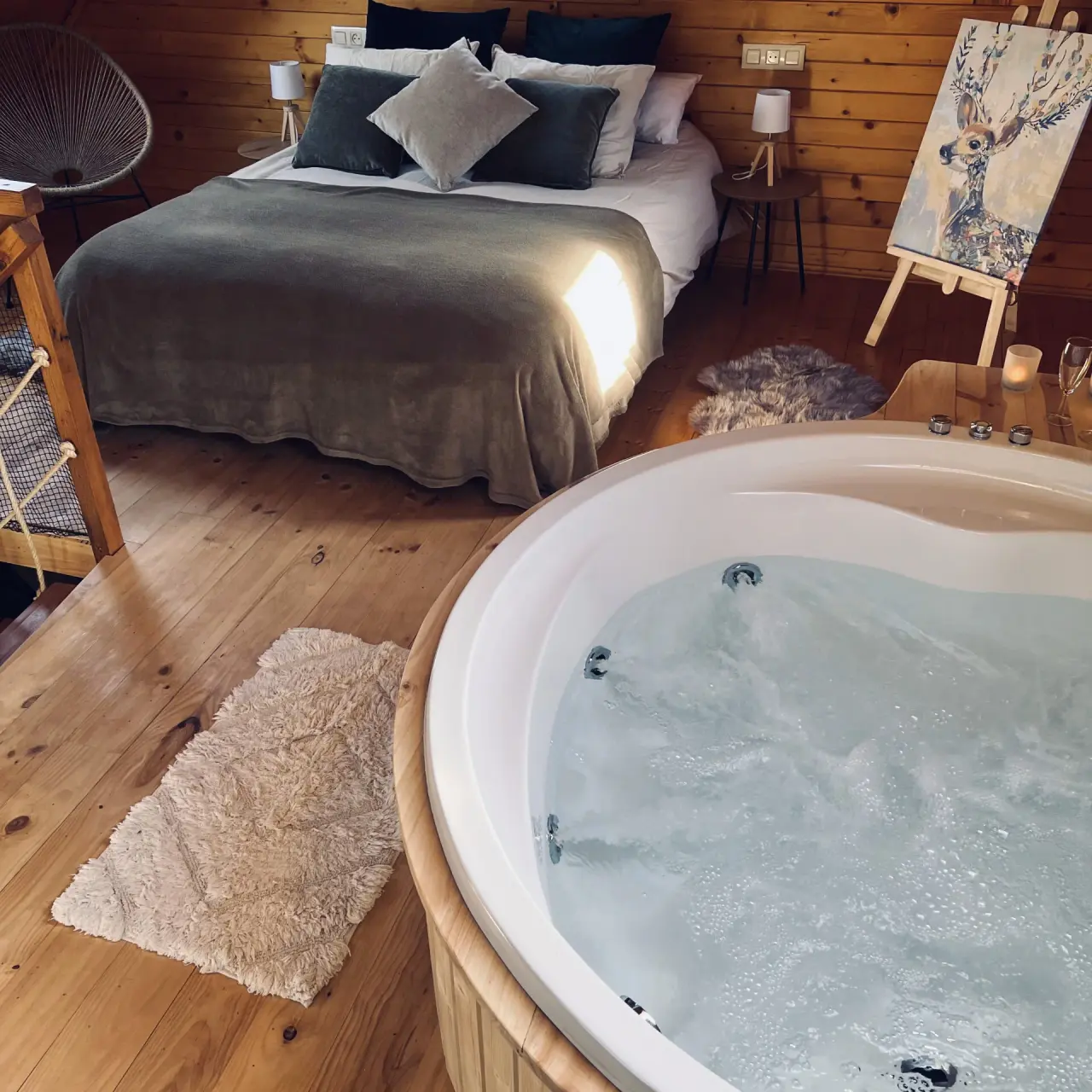Jacuzzi redondo de hidromasaje con agua burbujeante en primer plano, dentro de una habitación con paredes de madera