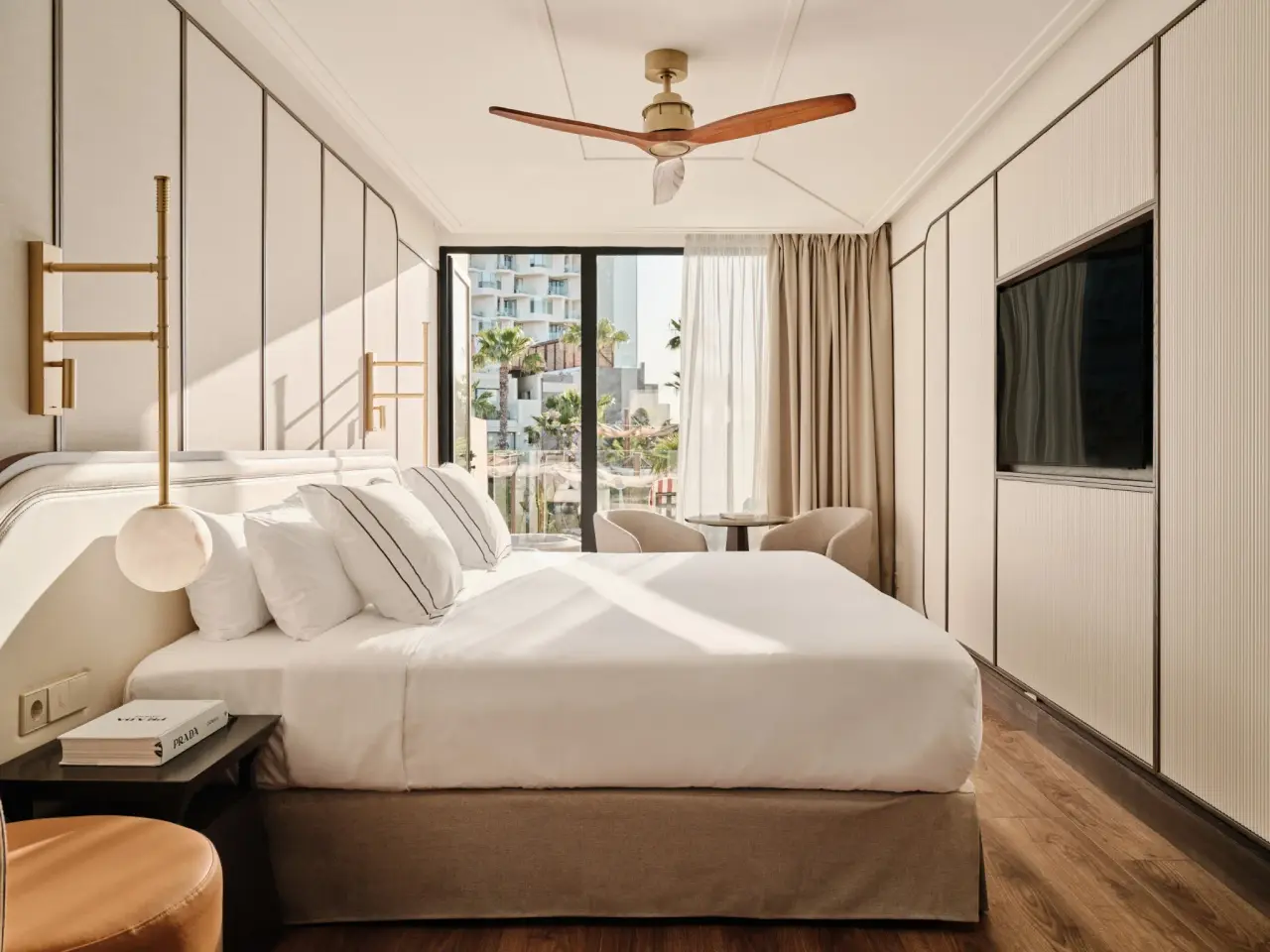 Habitación junior suite con cama king size vestida de blanco, cabecero beige, mesitas de noche, lámparas colgantes