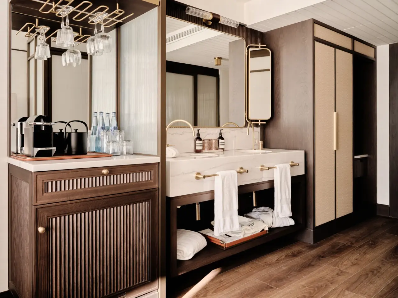 Interior de un baño moderno con mueble de madera oscura y encimera de mármol blanco que incluye una máquina de café