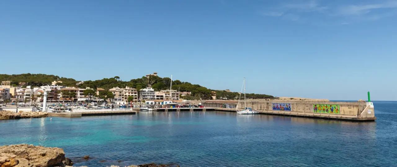Vista panorámica de un puerto deportivo con agua turquesa, muelles, barcos y edificios de una localidad costera