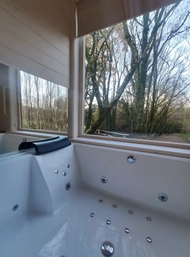 Jacuzzi privado interior de la Cabaña Lila con jets en las paredes y asiento, junto a una ventana grande que muestra