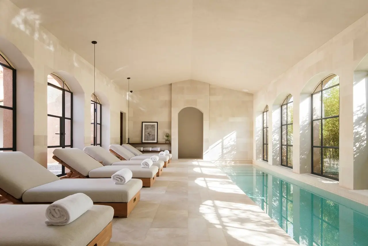 Interior de una piscina privada climatizada con tumbonas alineadas y toallas enrolladas en un espacio luminoso