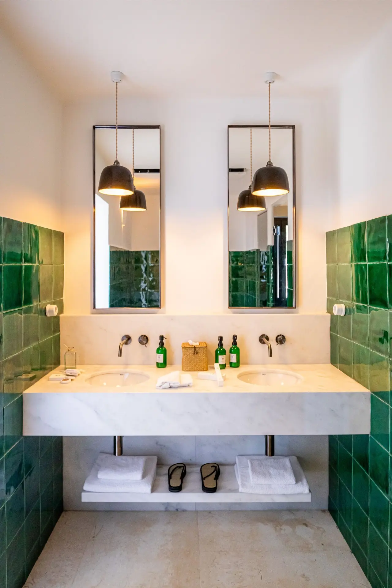 Baño con doble lavabo de mármol blanco sobre encimera, grifería mural, espejos rectangulares con marcos negros