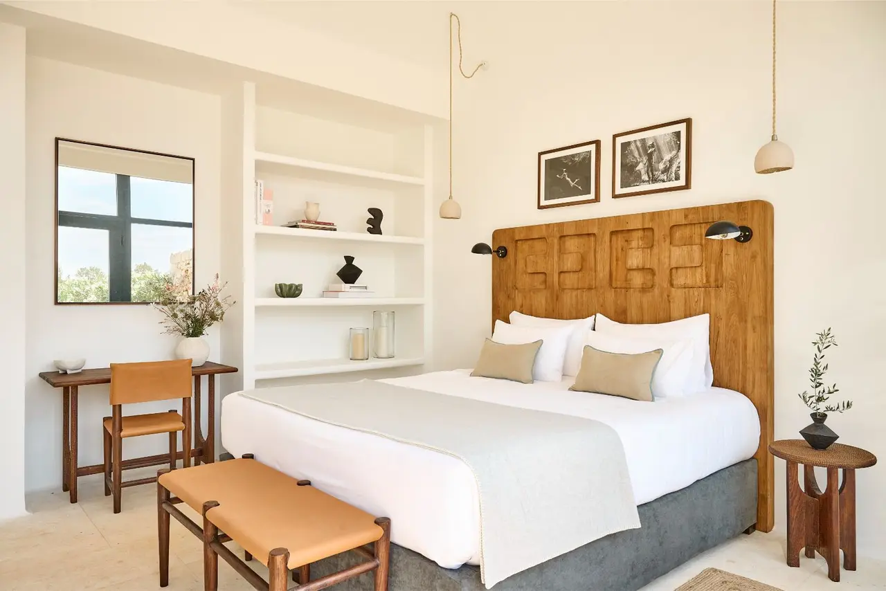 Habitación con cama doble, cabecero de madera tallada, estantería blanca empotrada, escritorio con silla, mesa