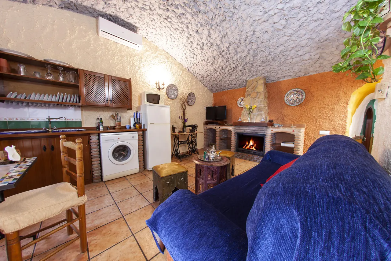 Interior de una habitación abovedada con paredes de piedra y textura, suelo de terracota, sofá azul en primer plano