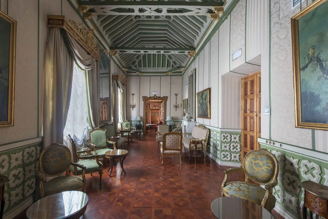 Interior de una suite junior con paredes decoradas en tonos verdes y blancos, suelo de terracota, techos altos
