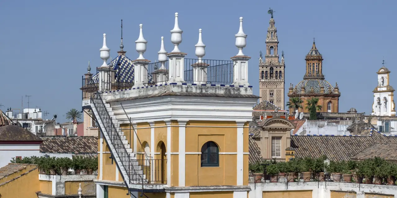 Vista panorámica de los tejados y monumentos de Sevilla desde una terraza, con la Giralda y otras torres al fondo bajo