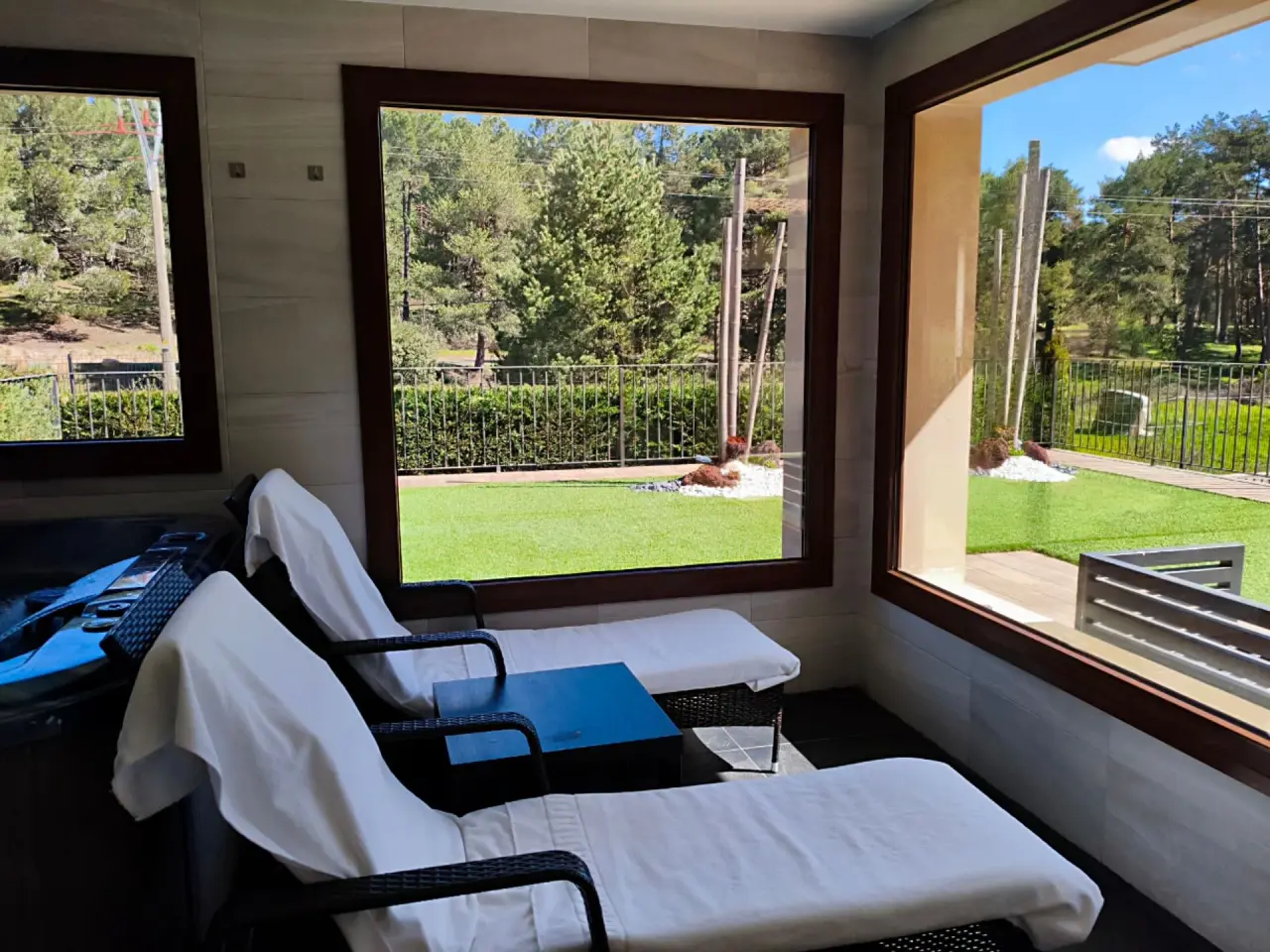 Interior de un spa privado con dos tumbonas acolchadas con toallas blancas, suelo de baldosas oscuras y grandes
