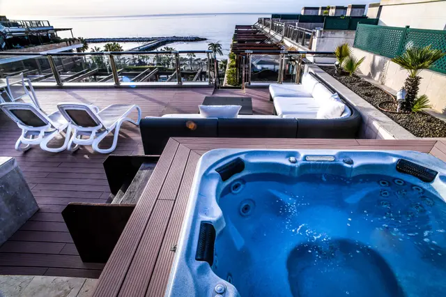 Gran Hotel Guadalpin Banus: Jacuzzi en terraza privada de suite con vistas al mar, rodeado de tumbonas blancas, sofá exterior y barandilla de crista