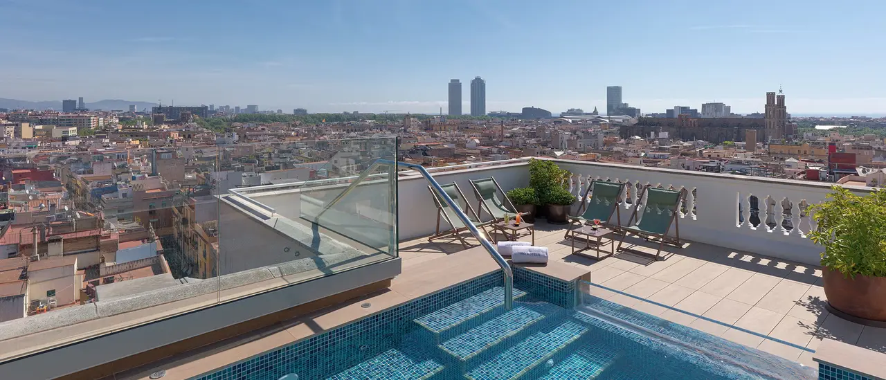 Vista panorámica de la ciudad desde una terraza con piscina en la azotea, bajo un cielo despejado.