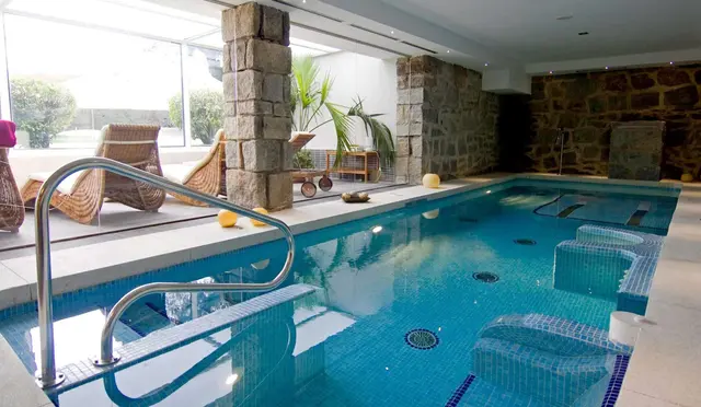Hacienda Los Robles: Interior de un spa privado con piscina rectangular de agua azul, bordes de mosaico, barandilla metálica de acceso, asien