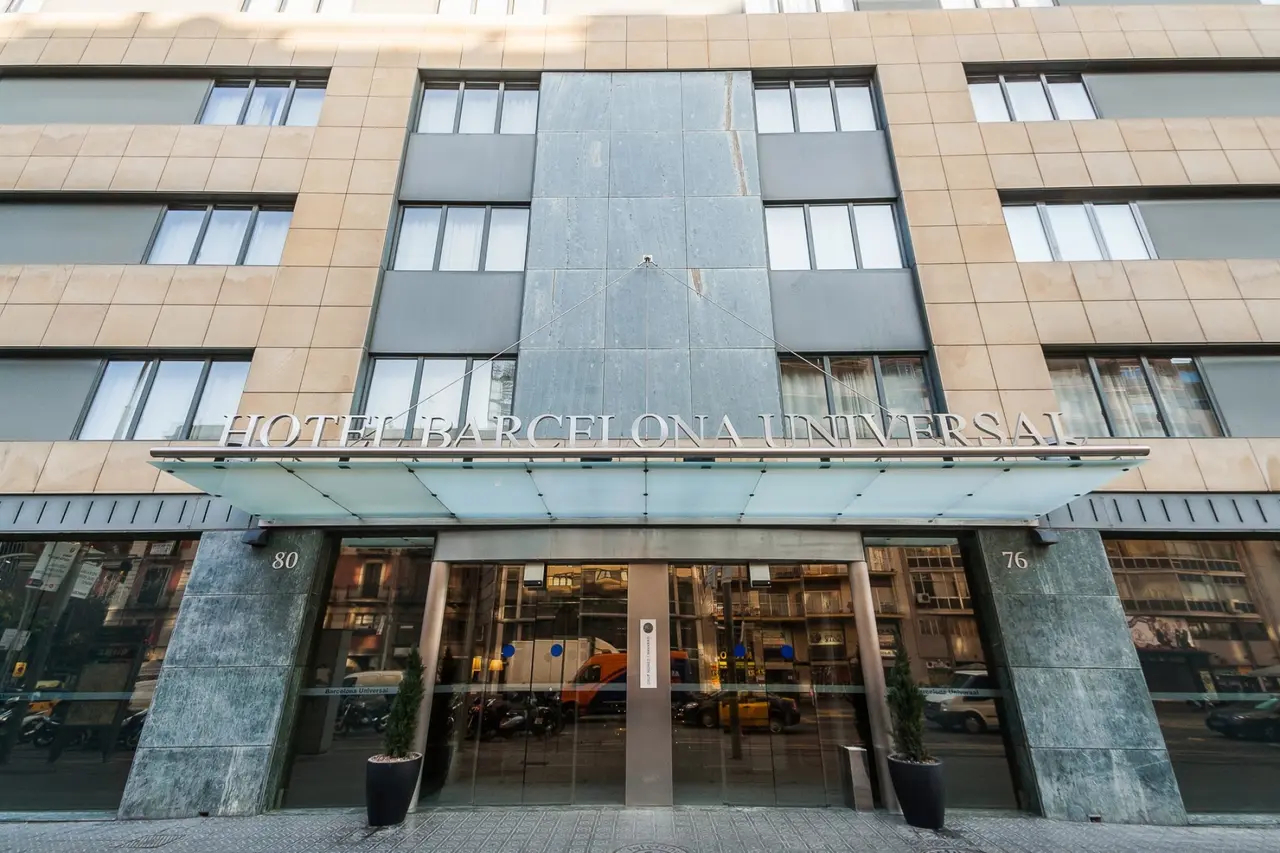 Fachada principal del Hotel Barcelona Universal, un edificio de varias plantas con revestimiento de piedra y paneles