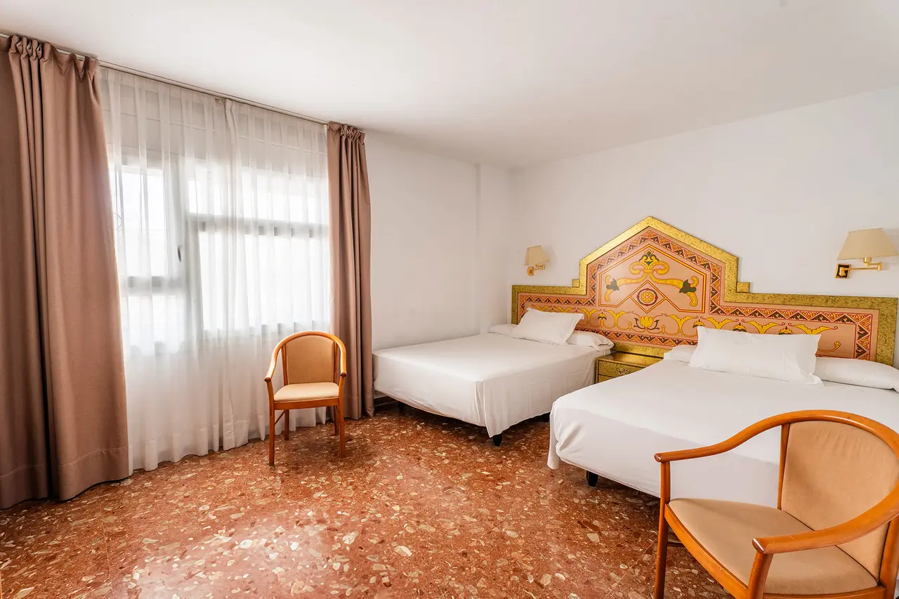 Habitación de hotel con dos camas individuales, cabeceros decorados con motivos geométricos y florales en tonos