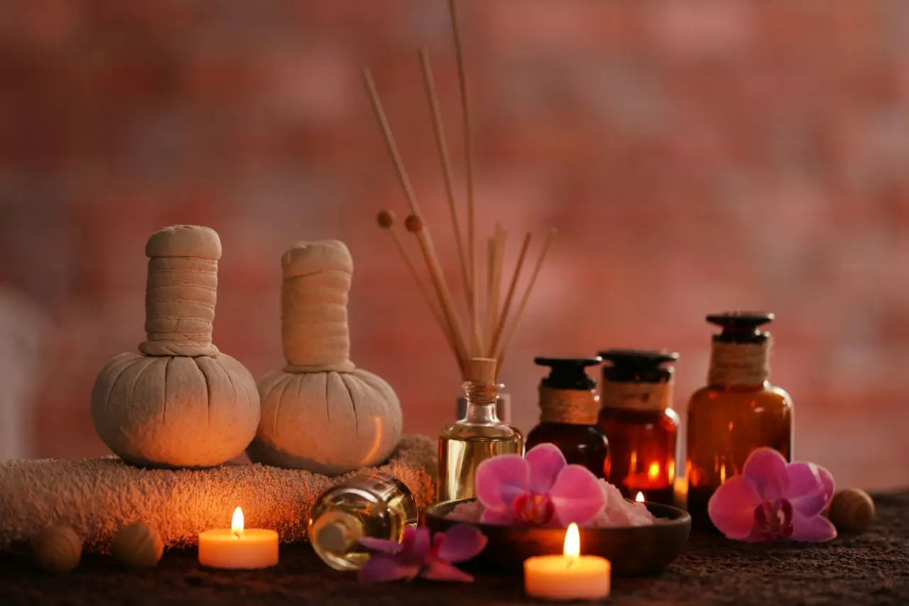 Vista de accesorios de spa privado: dos bolsas herbales envueltas, difusor de aroma con varillas, botellas de aceites