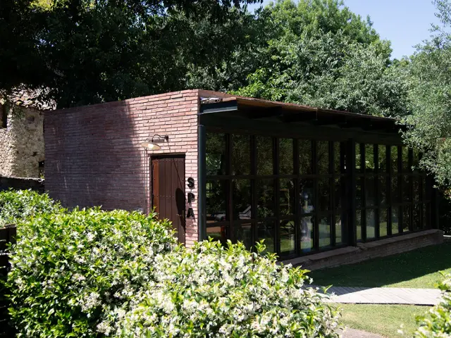 Edificio rectangular de ladrillo visto con grandes ventanales y puerta de madera, con el rótulo vertical “SPA”