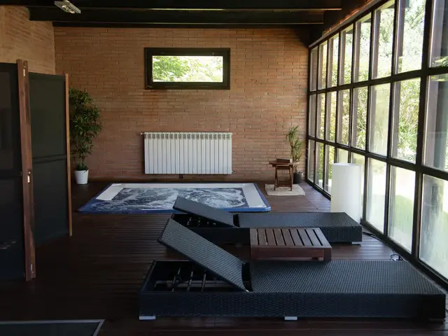 Interior de un spa privado con suelo de madera oscura, paredes de ladrillo visto, grandes ventanales que dan