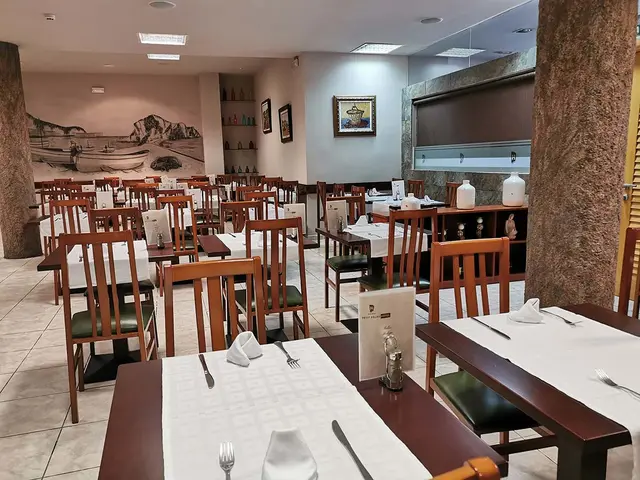 Interior de un comedor de hotel con mesas vestidas, sillas de madera y decoración en las paredes.