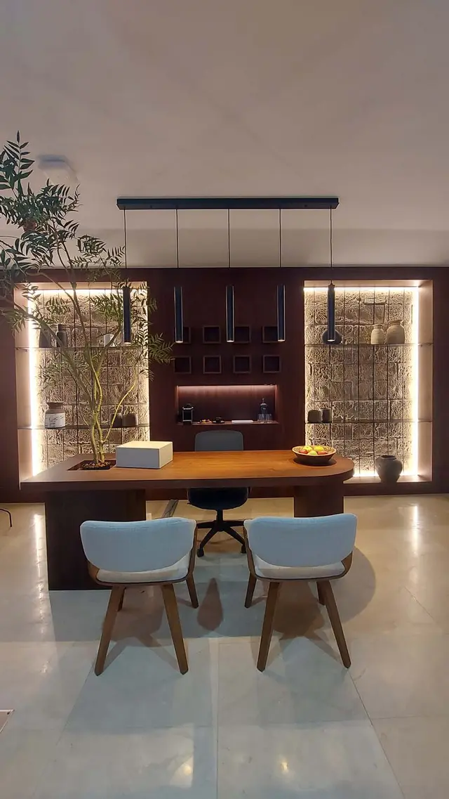 Espacio interior de un spa privado con una mesa de madera central rodeada de sillas claras, estanterías iluminadas