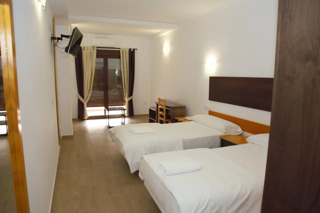 Habitación de hotel con dos camas individuales separadas, cabeceros de madera oscura, sábanas blancas y toallas