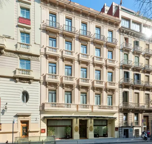 Fachada exterior de un edificio de varios pisos de estilo clásico con balcones, puertas y ventanas, ubicado