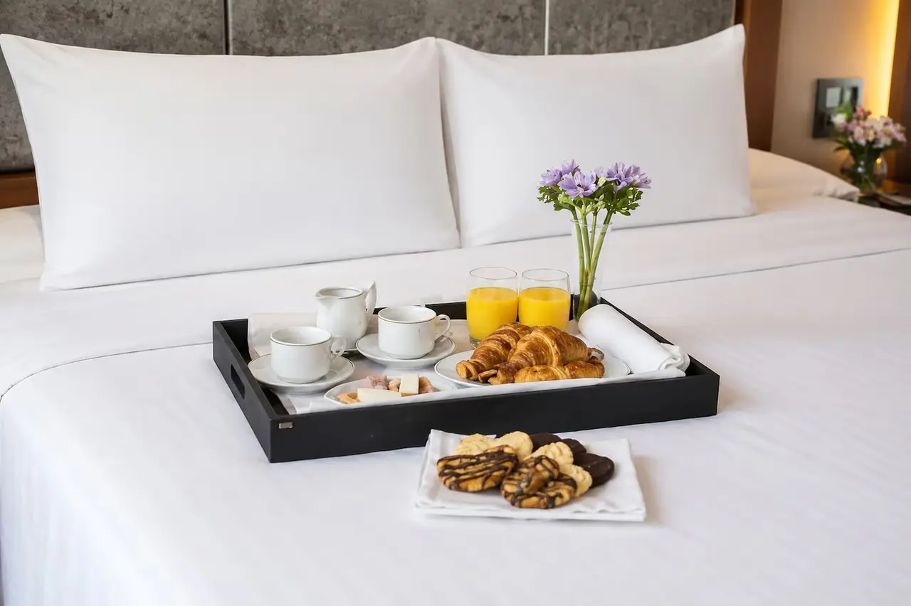Vista de una cama king size con sábanas blancas y dos almohadas grandes.