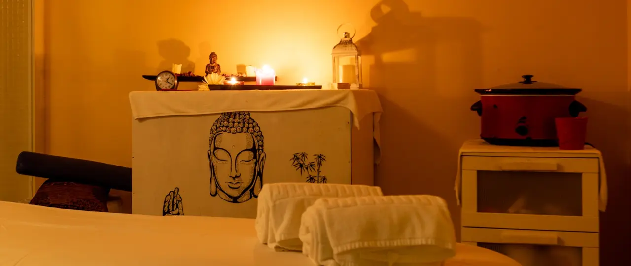 Interior de una habitación con una mesa cubierta por una tela blanca que tiene un dibujo de Buda, sobre la que hay