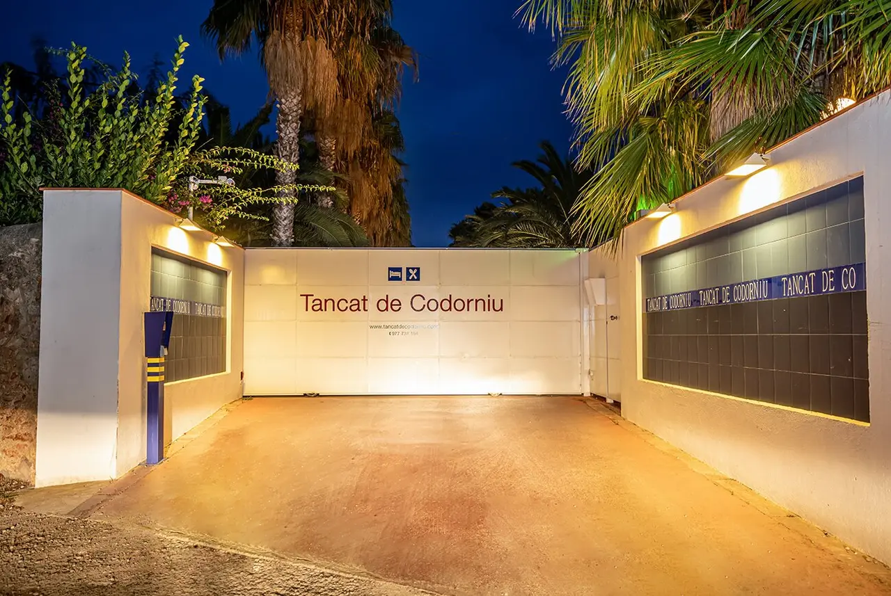Entrada principal al Tancat de Codorniu por la noche, con un muro blanco iluminado que muestra el nombre