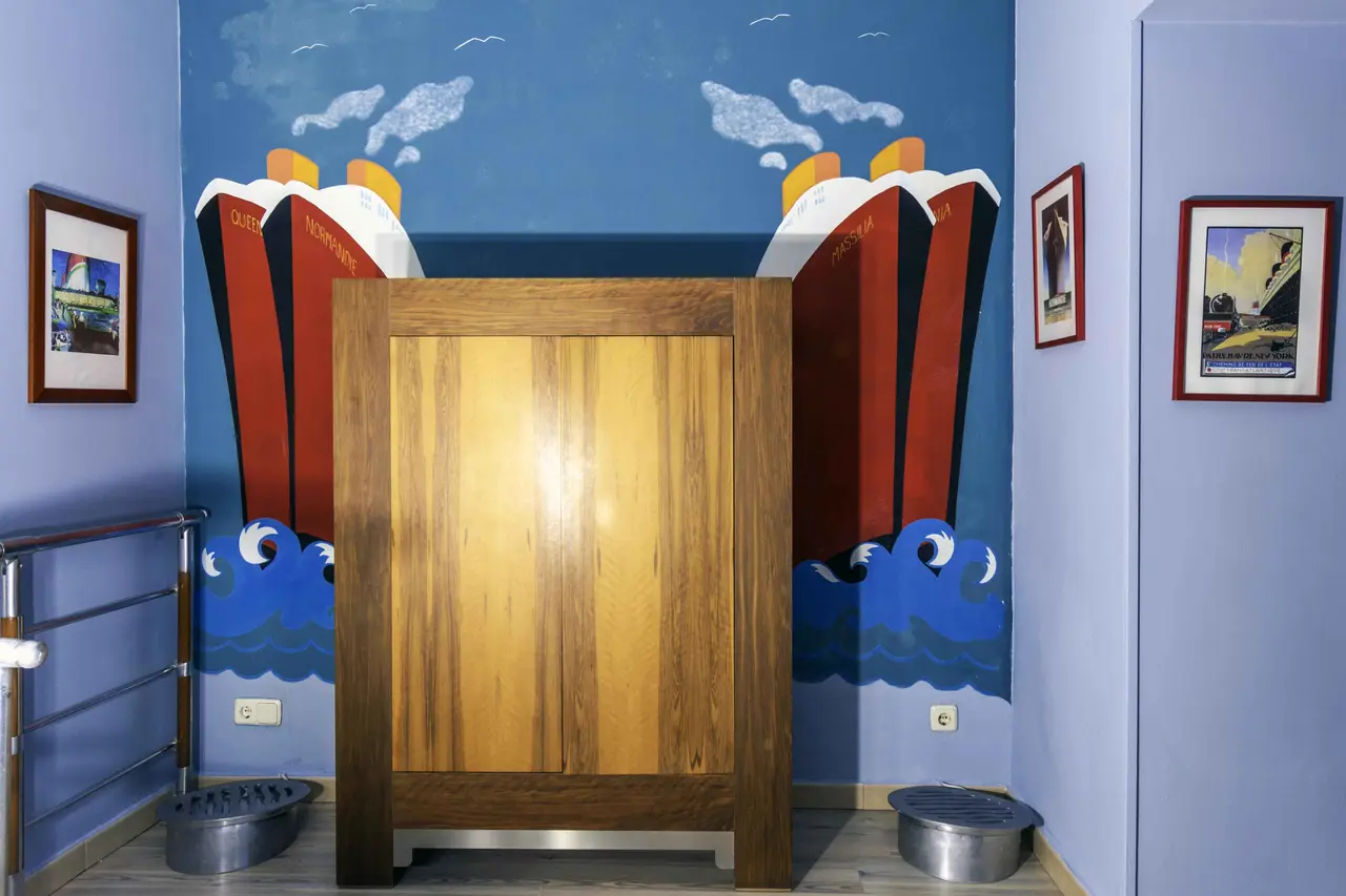 Mural pintado en la pared de una habitación con dos barcos de vapor rojos y blancos navegando en un mar azul con olas