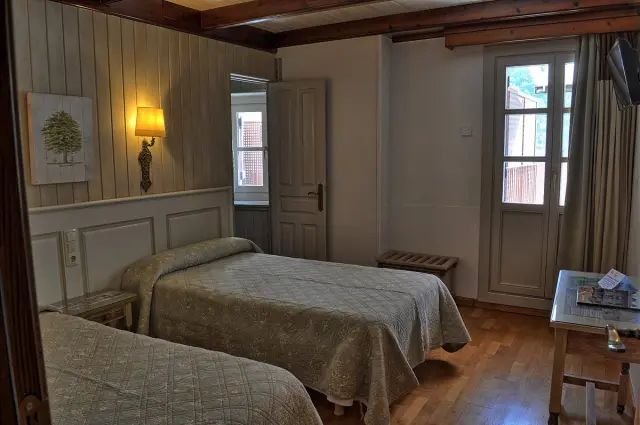Vista de una suite junior con dos camas individuales, paredes con paneles de madera y escayola, suelo de parquet