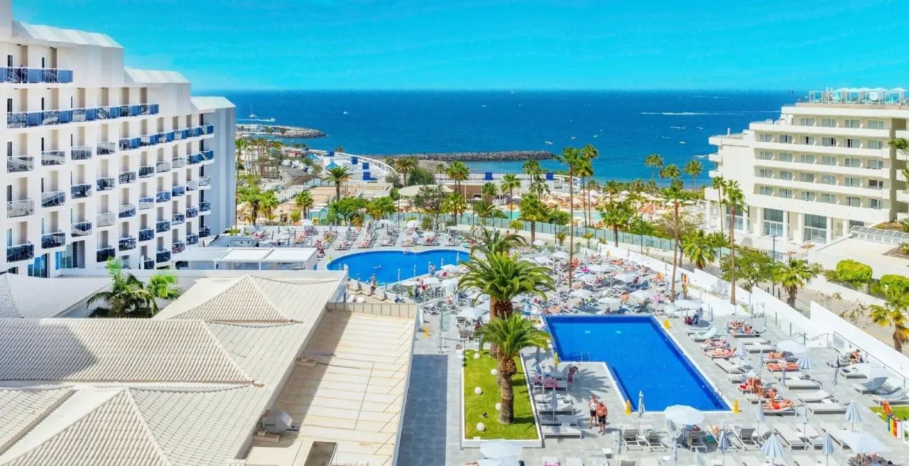 Vista panorámica desde una suite en Hovima Cool Costa Adeje, mostrando dos piscinas exteriores rodeadas de tumbonas