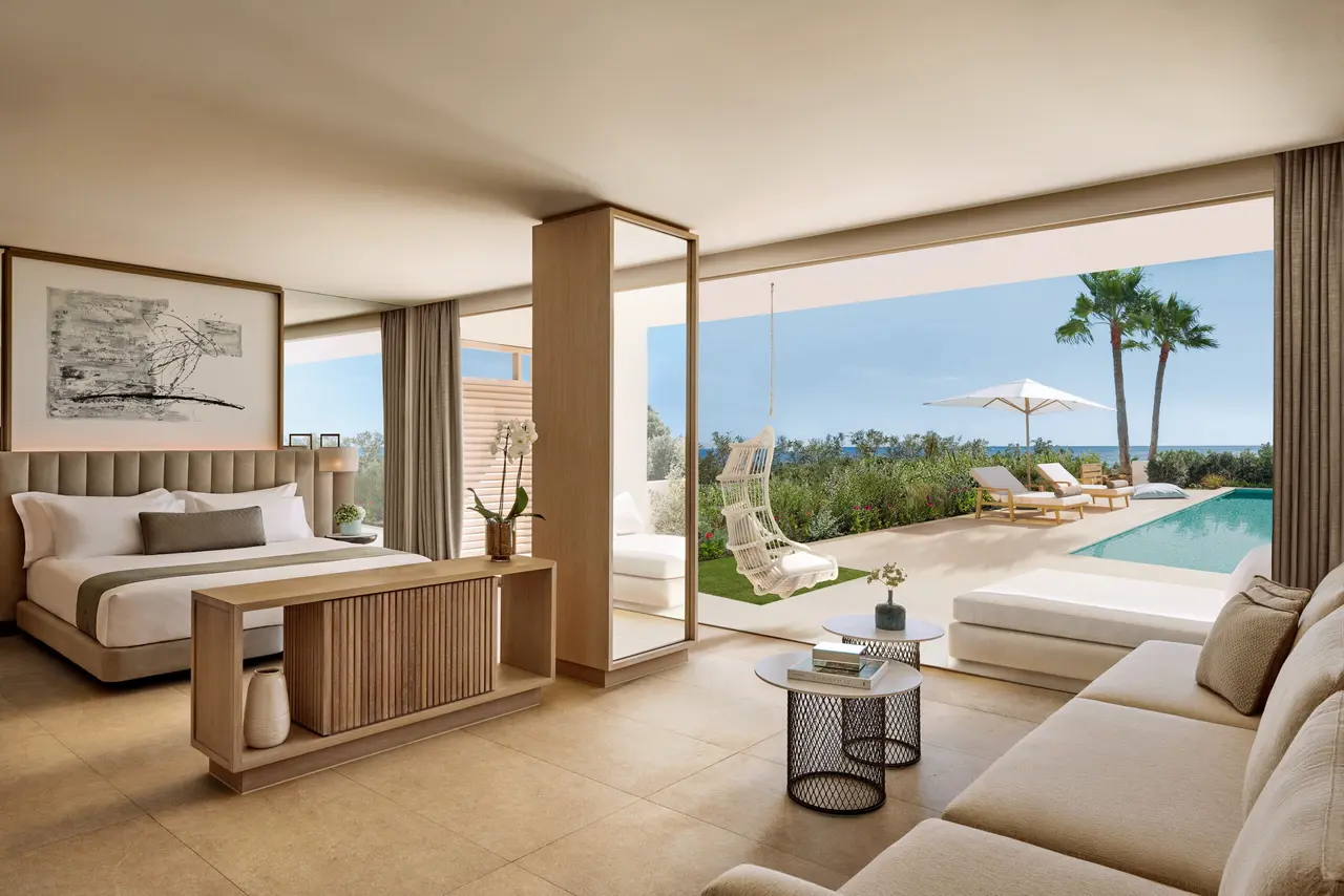Vista desde el interior de una suite hacia una terraza con piscina privada rectangular de agua azul, rodeada