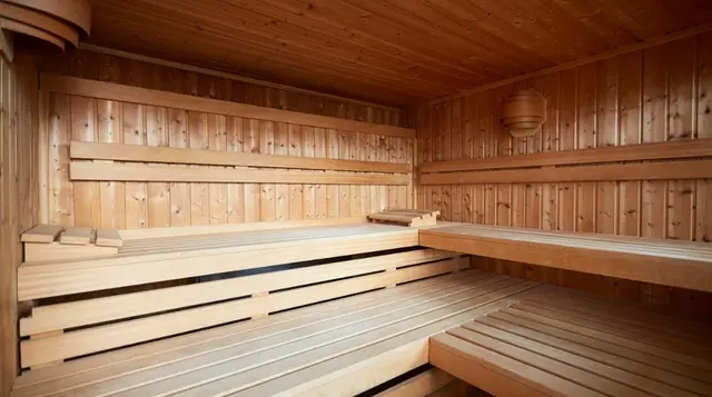 Interior de una sauna de madera con bancos escalonados en forma de L, paredes y techo revestidos de listones de madera