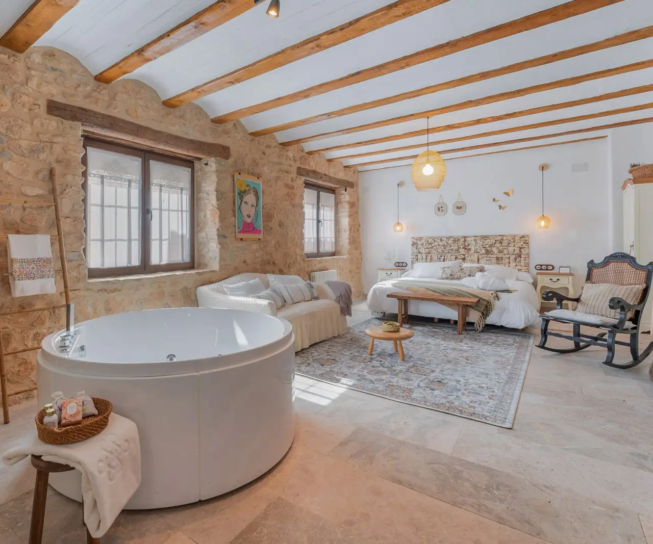 Vista de una suite rural con un jacuzzi privado blanco de gran tamaño en primer plano, junto a una zona de estar