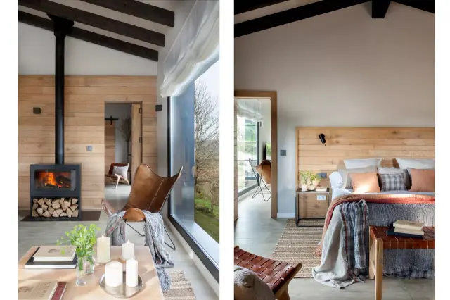 Interior de una habitación con paredes de madera clara, una chimenea negra encendida, un sillón de cuero marrón junto a 