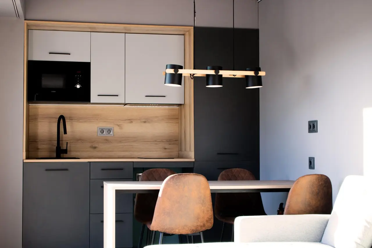 Espacio interior con cocina integrada, barra de desayuno con taburetes de cuero marrón, armarios en tonos claros