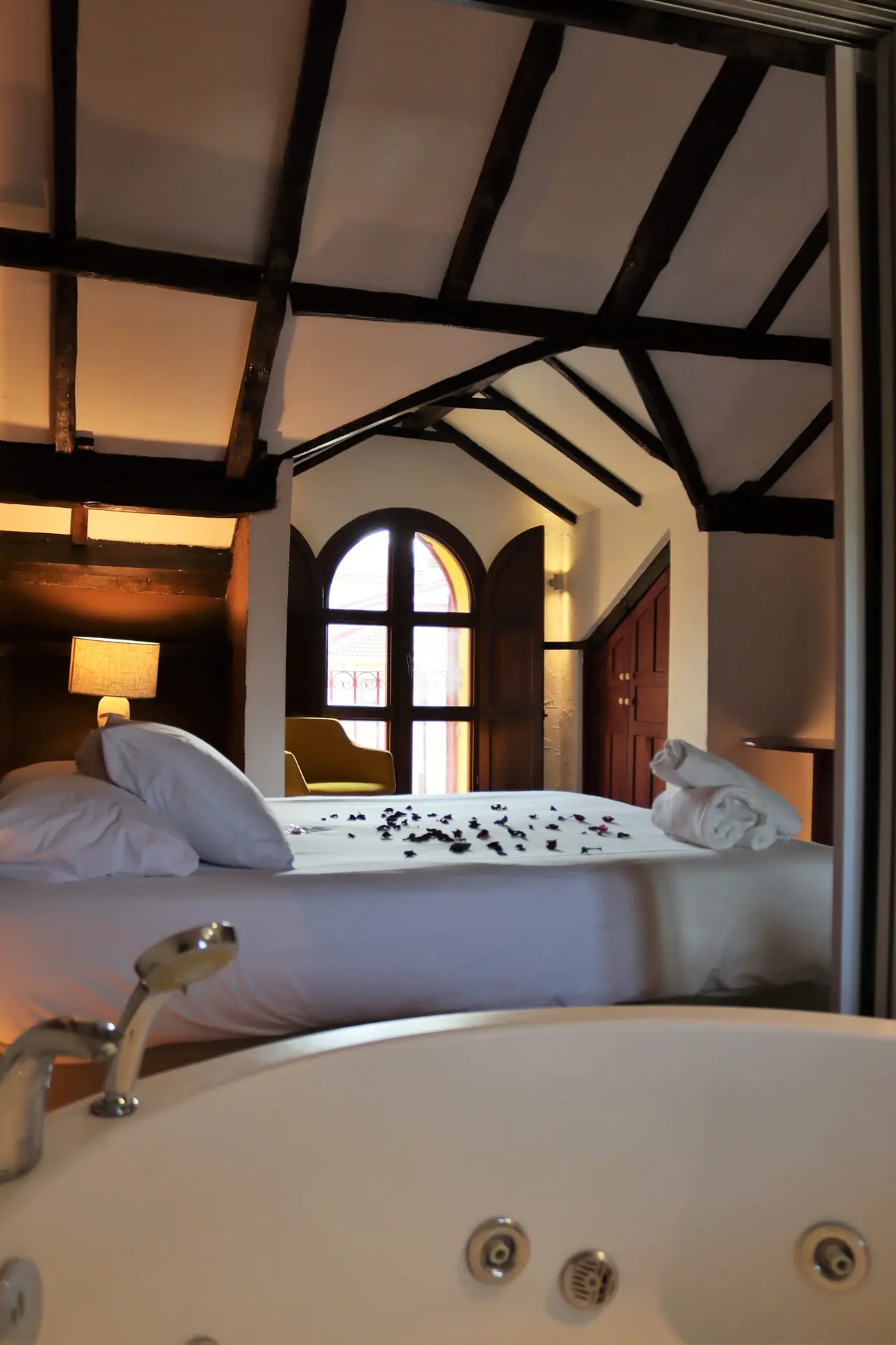 Vista de un jacuzzi en primer plano dentro de una habitación rústica con techo de vigas de madera.