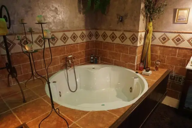 Jacuzzi blanco empotrado en un baño con paredes de azulejos terracota y una franja decorativa.
