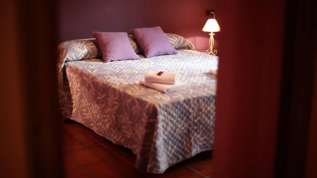 Vista de una habitación con una cama doble cubierta por una colcha estampada en tonos azules y blancos, dos almohadas