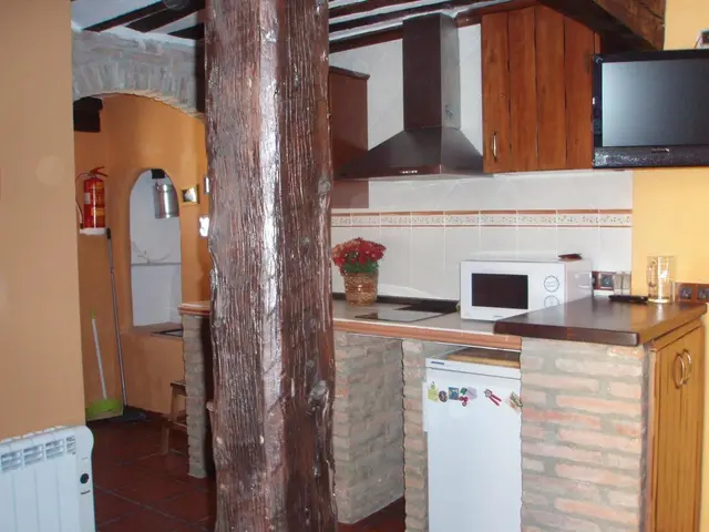 Interior de una habitación con cocina integrada, encimera de ladrillo visto, microondas, campana extractora, nevera
