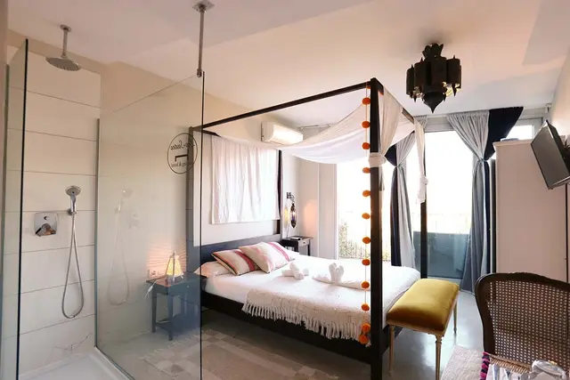Habitación con cama de dosel, ducha a ras de suelo y zona de baño integrada.