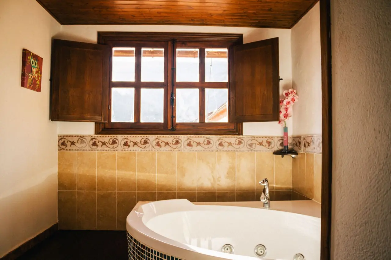 Jacuzzi interior blanco de forma redondeada con grifo y jets visibles, situado en una habitación con paredes