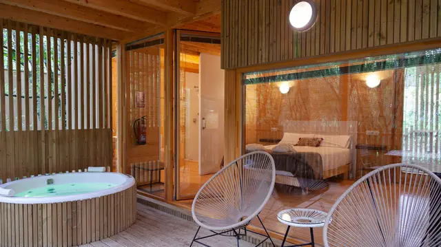 Jacuzzi circular blanco en terraza de madera privada rodeado de paneles de madera verticales, con vistas a un interior