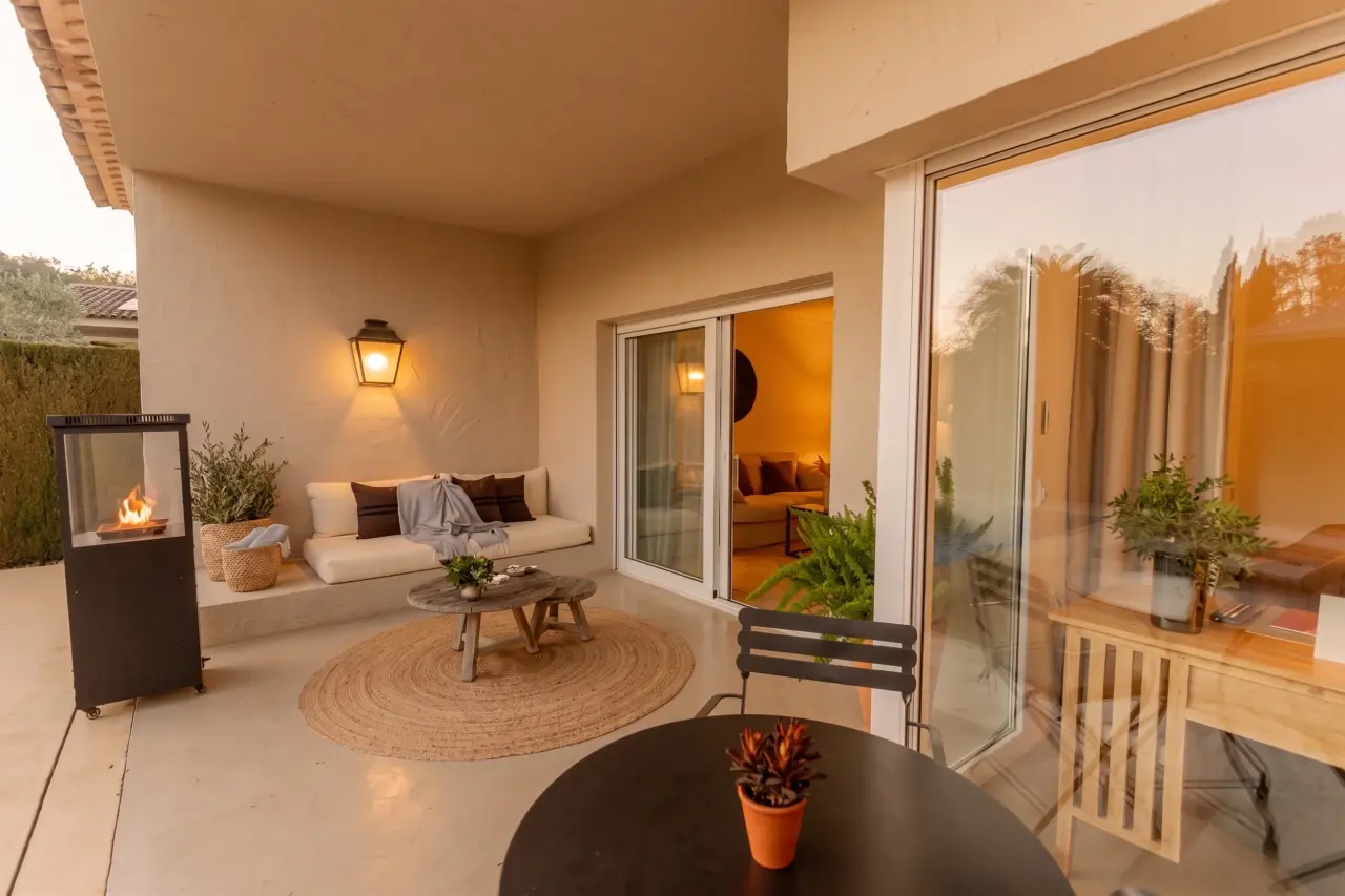 Terraza exterior de una suite con suelo de baldosa clara, zona de estar con sofá blanco y mesa de centro