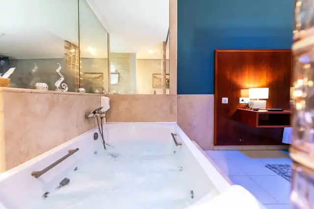 Vista de un jacuzzi rectangular blanco con agua burbujeante y espuma, instalado en una habitación.