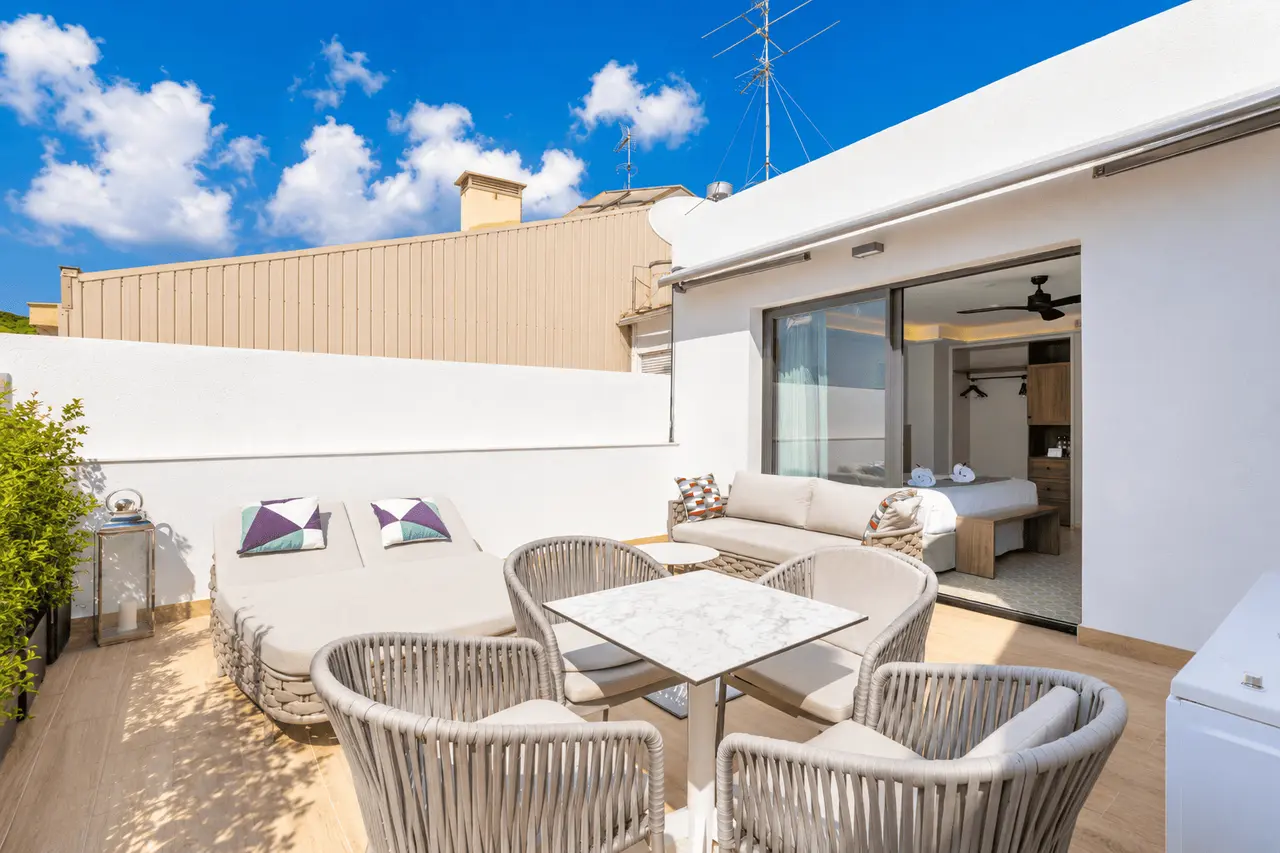 Terraza exterior de una suite con suelo de madera, mobiliario de exterior compuesto por un sofá, sillones y una mesa