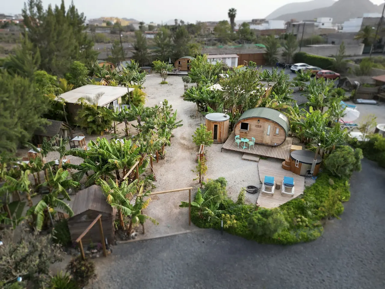 Vista aérea de un complejo de alojamientos ecológicos con cabañas de madera, terrazas, vegetación abundante y caminos