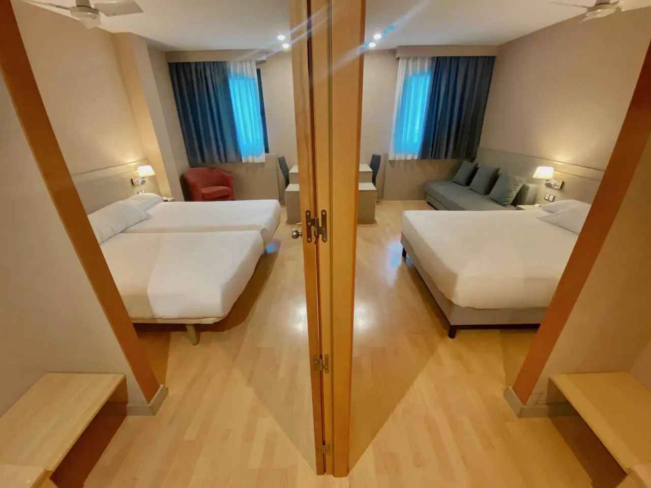Vista desde la puerta de entrada a una habitación de hotel con dos camas separadas a la izquierda y una cama doble